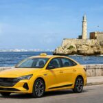 Taxi privado en La Habana: taxi amarillo moderno en el Malecón frente al Morro